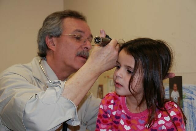 A Pediatrician in Houston is examining a little girl's ear.
