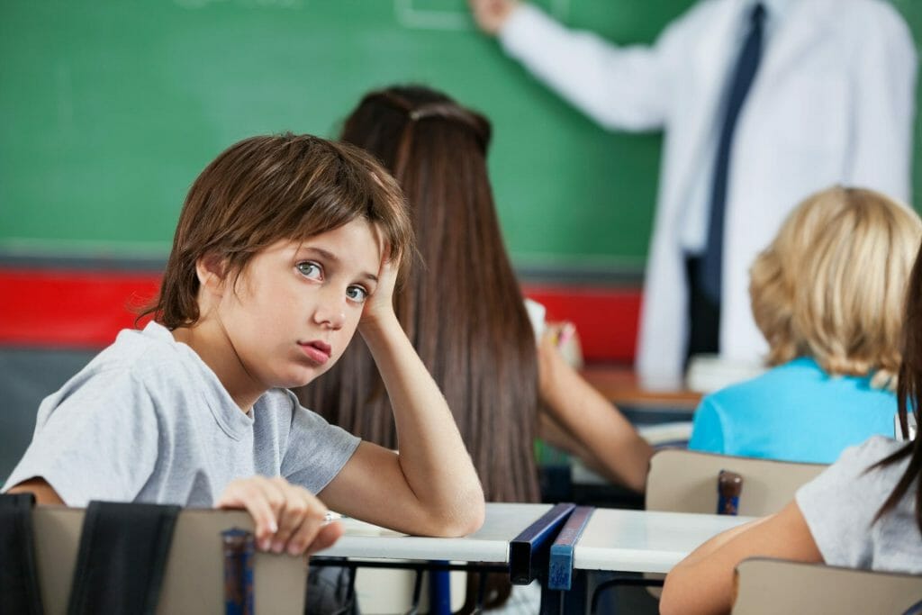 Un niño está sentado frente a un escritorio en un salón de clases.