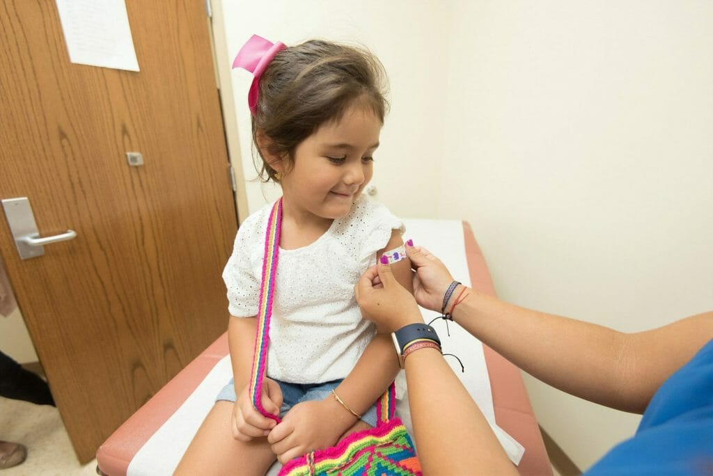 A young girl is getting a vaccine at a doctor's office.