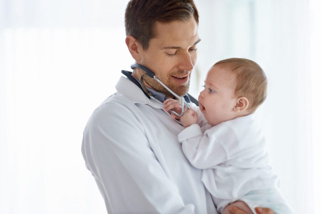A doctor holding a baby with a stethoscope.