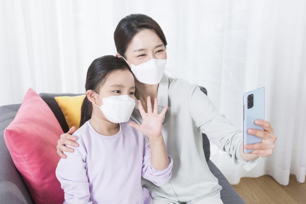 A mother and daughter wearing face masks during the pandemic while taking a selfie.