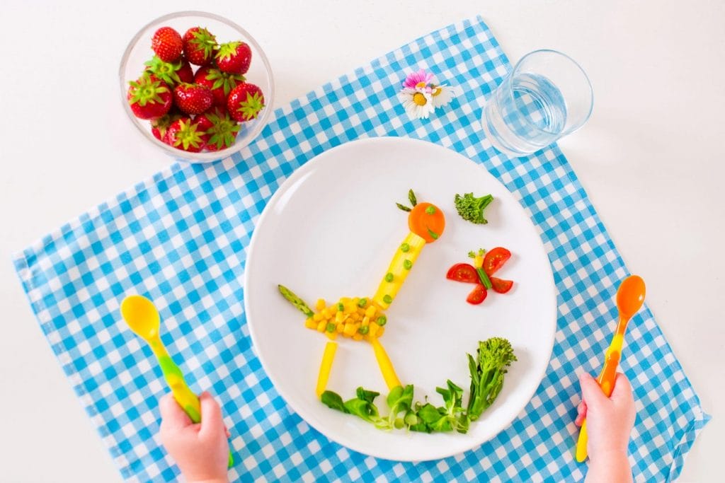 A plate with a giraffe and strawberries on it, providing expert nutrition for children.