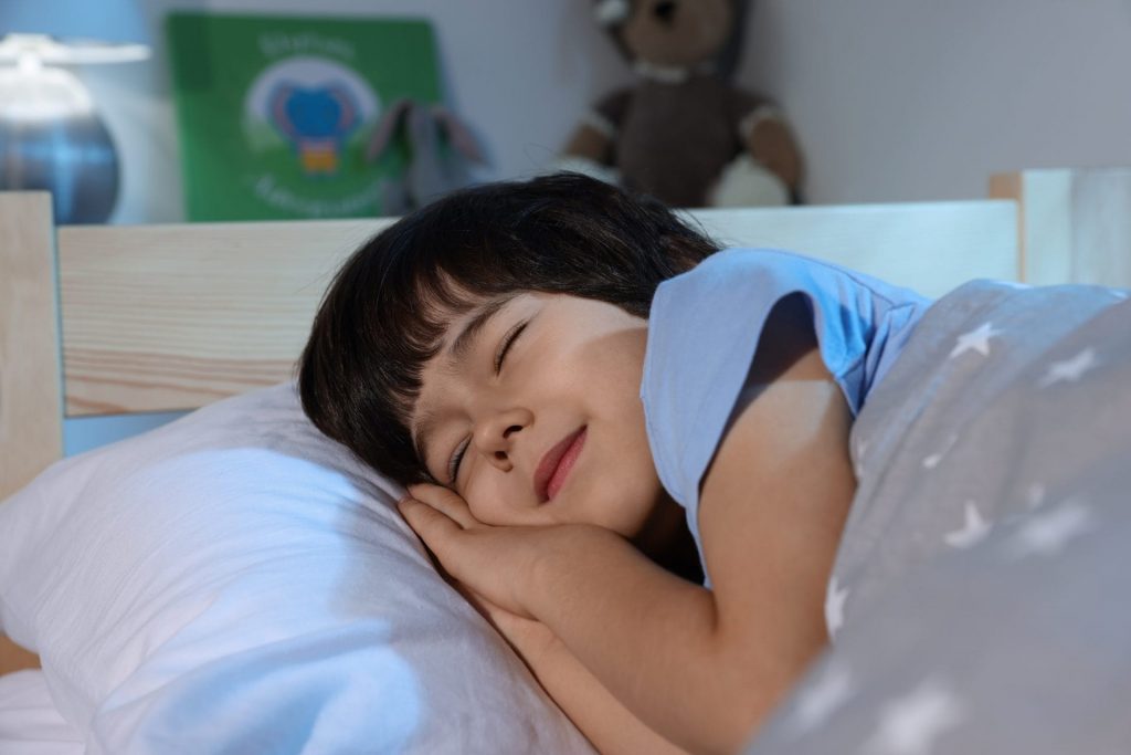 In a children's story, a young boy peacefully sleeps in his bed.